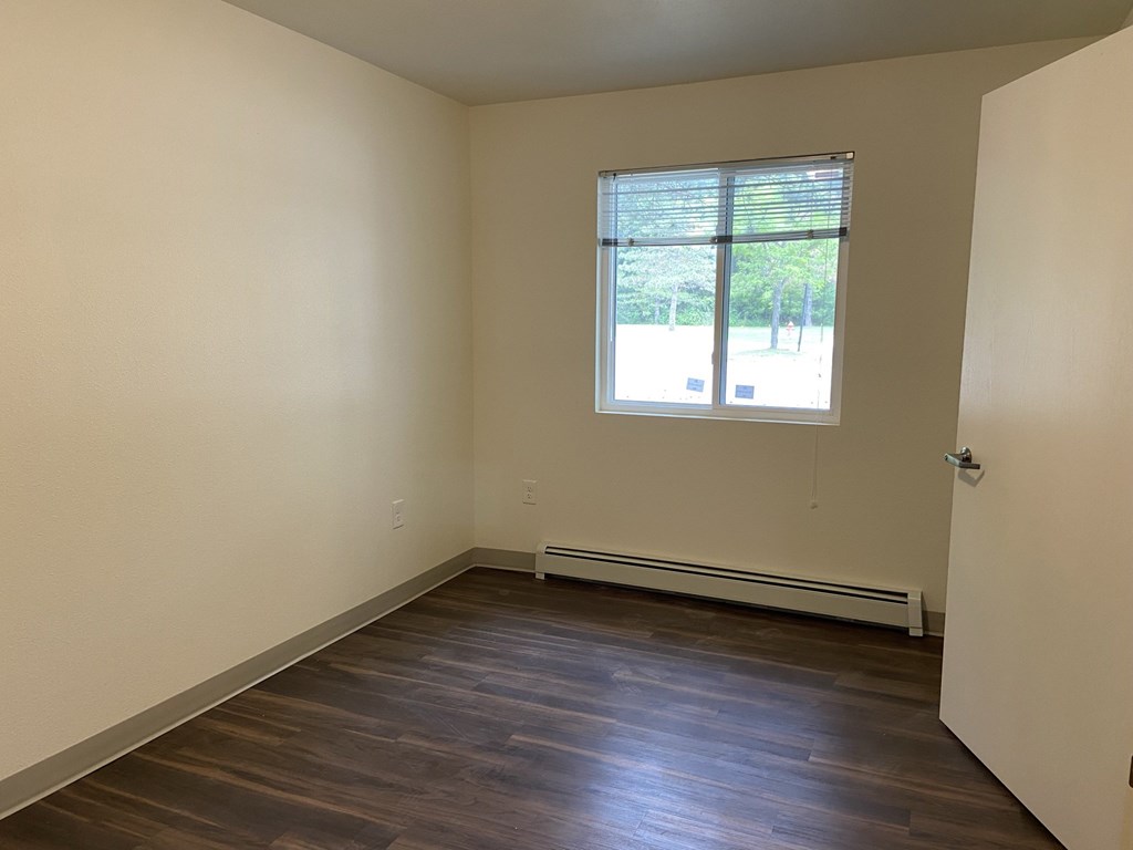 an empty room with wooden floors and a window